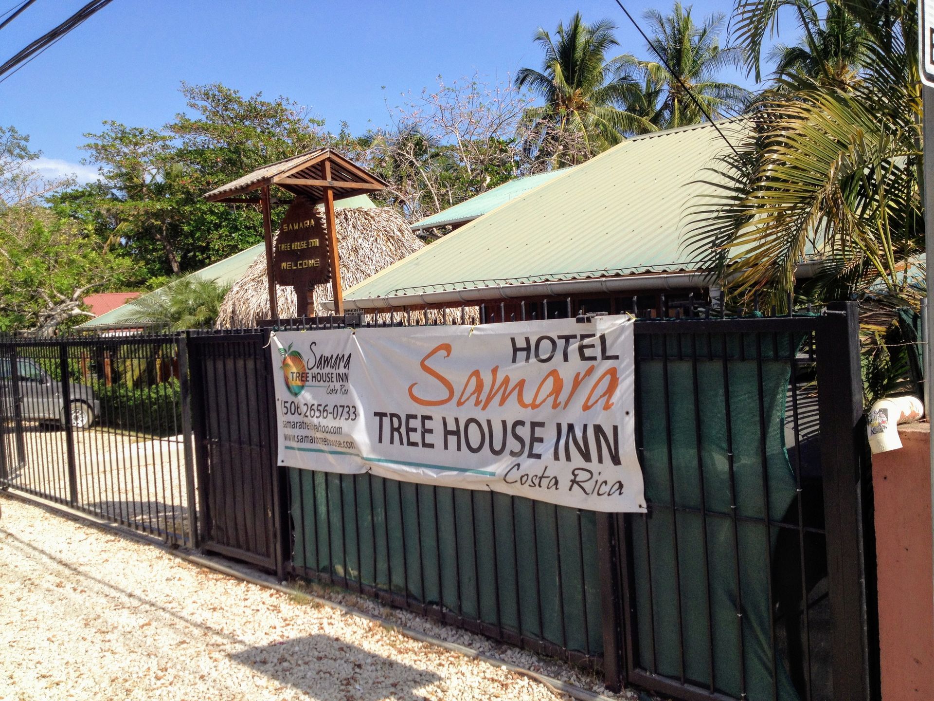 Hotel Samara Tree House Inn in Costa Rica, with a sign on a metal gate and a thatched roof over the entrance.