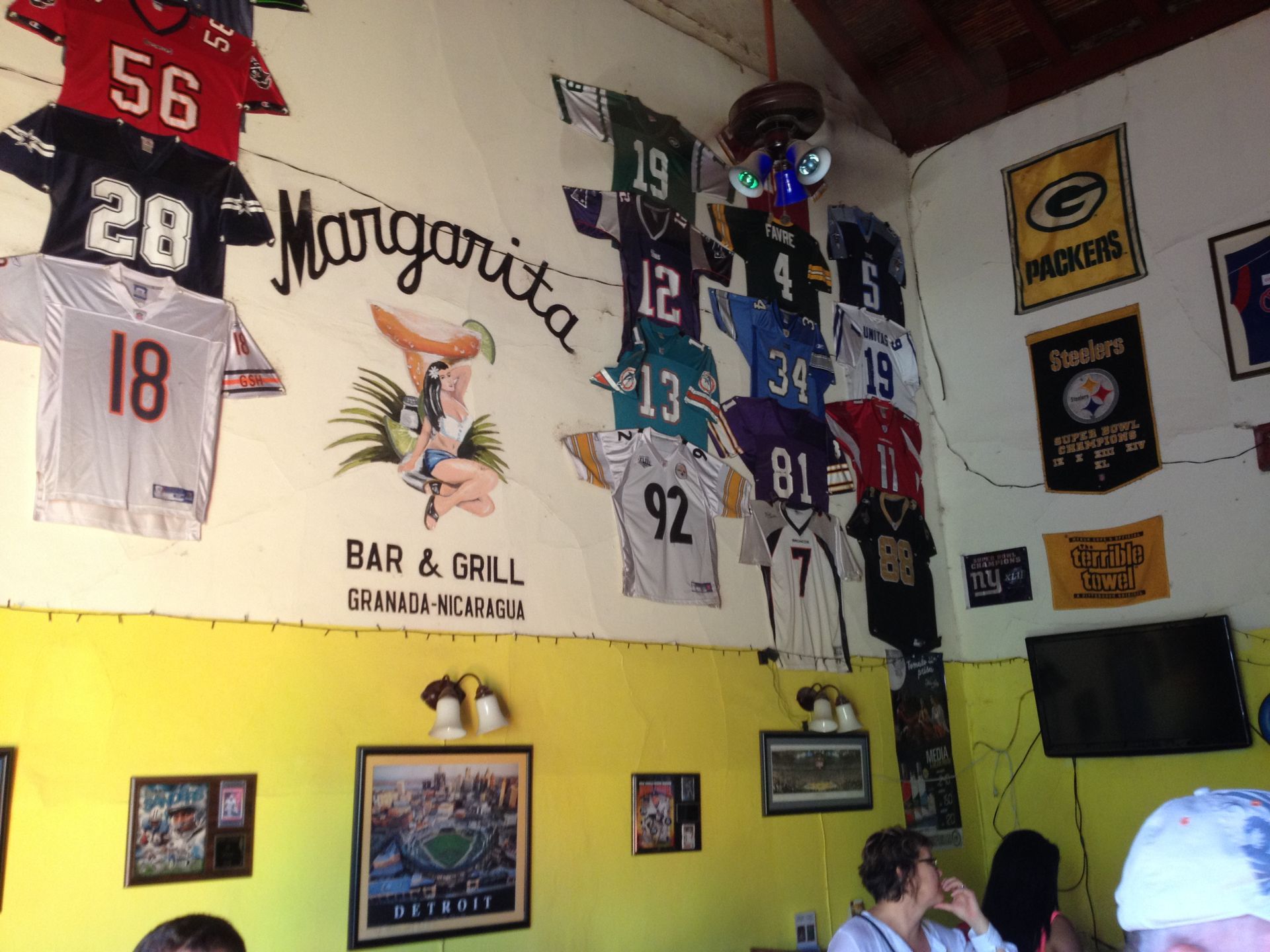 Margarita Bar & Grill with sports jerseys hanging on the wall. Yellow and white walls, people seated.