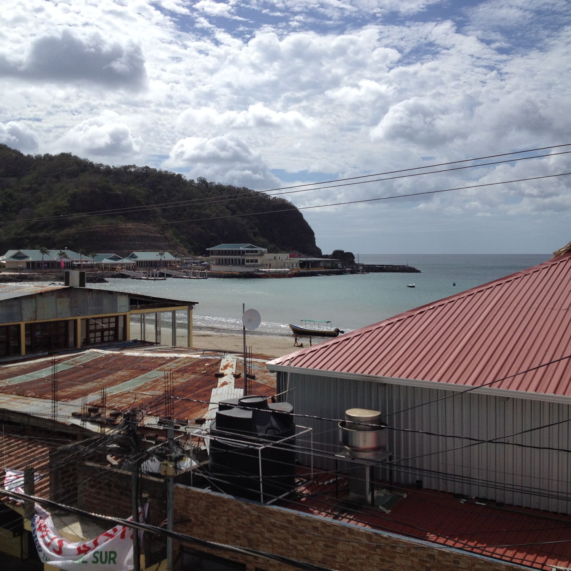 Coastal town with buildings, a beach, water, and cloudy sky.
