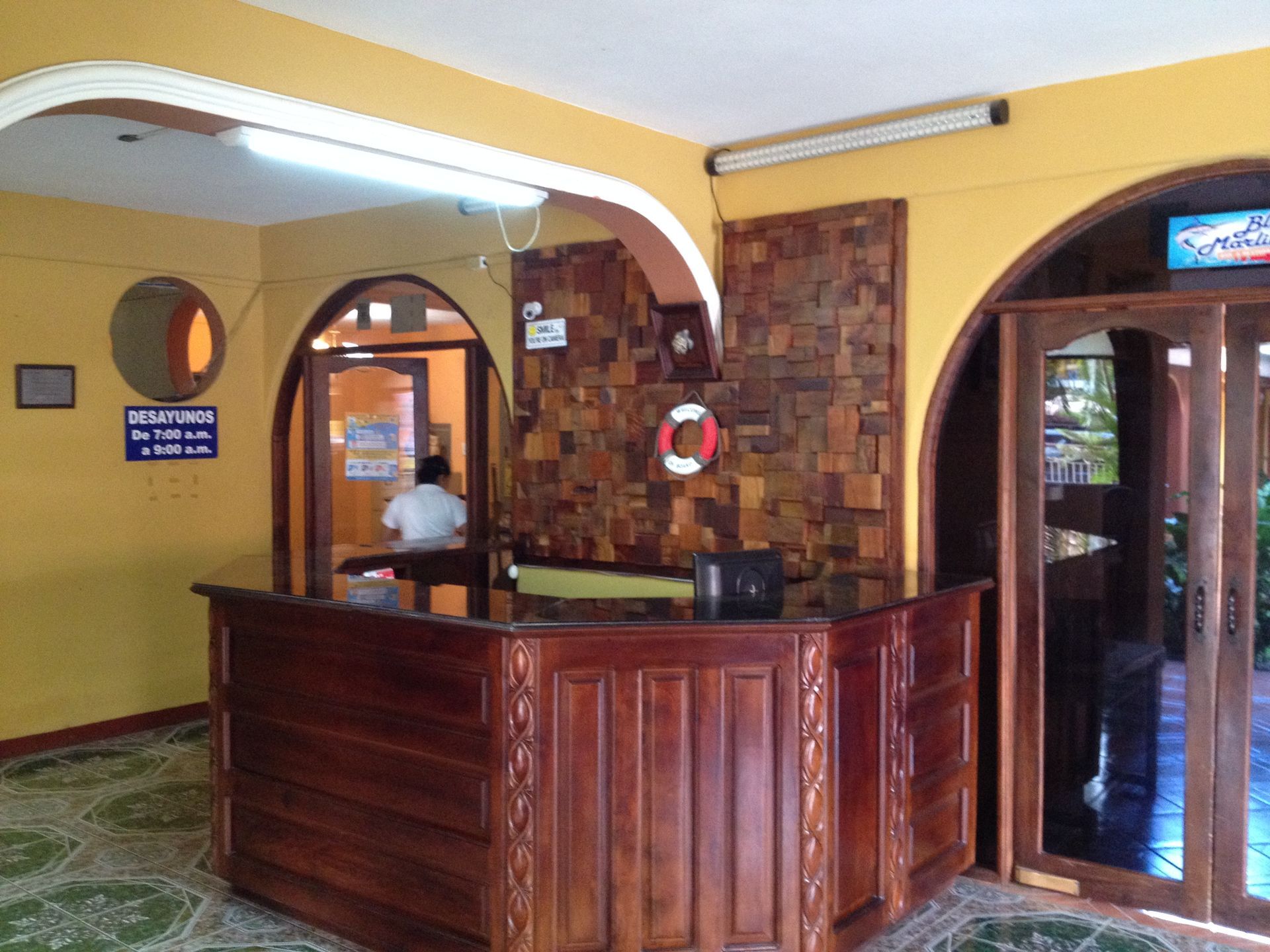 Hotel reception desk with wooden counter, yellow walls, and front desk clerk.