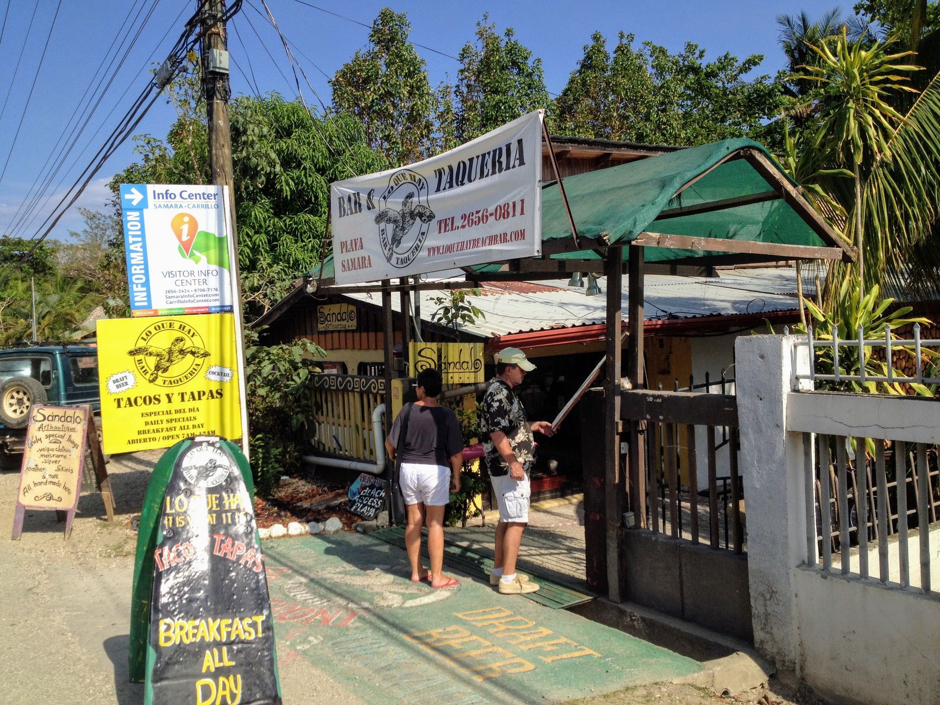 Taco stand entrance with people. Signage includes 