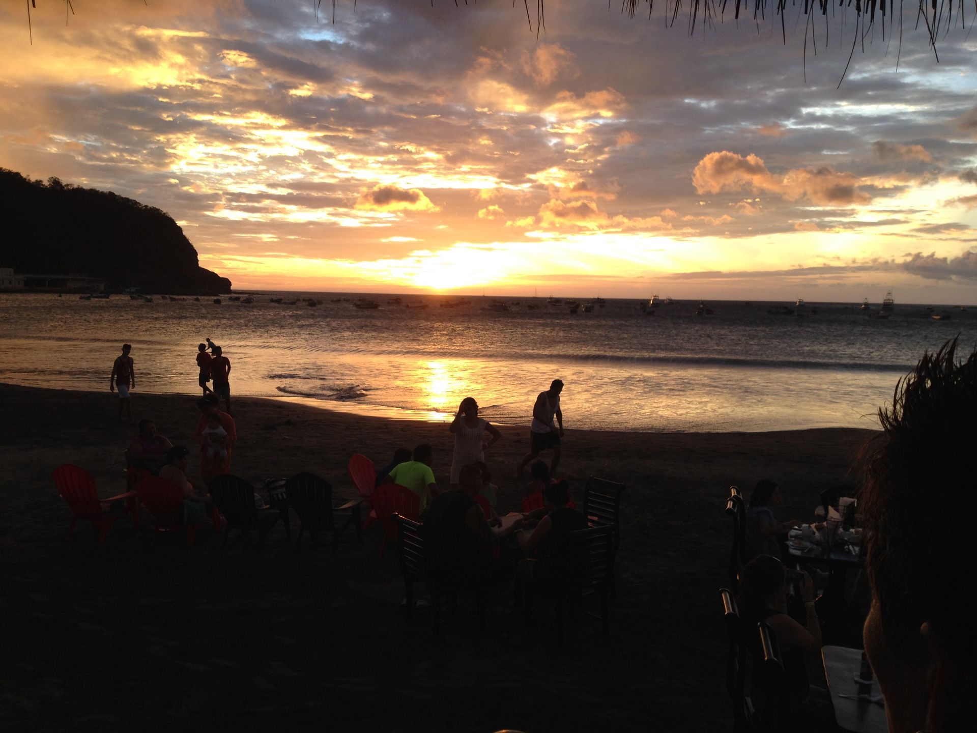 Beach sunset, silhouetted people, golden light reflecting on the water.