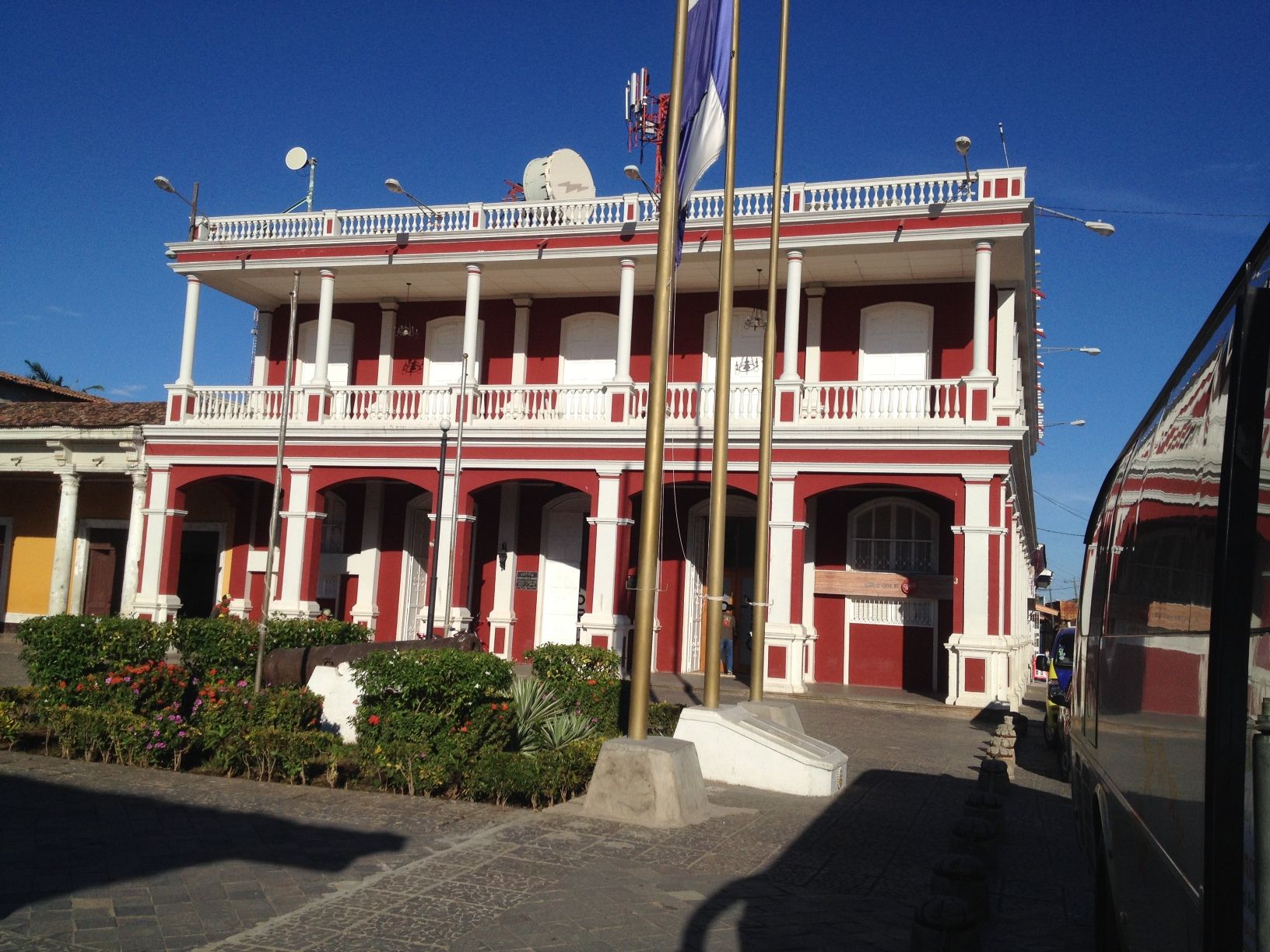 Red and white colonial-style building with a balcony, under a blue sky.