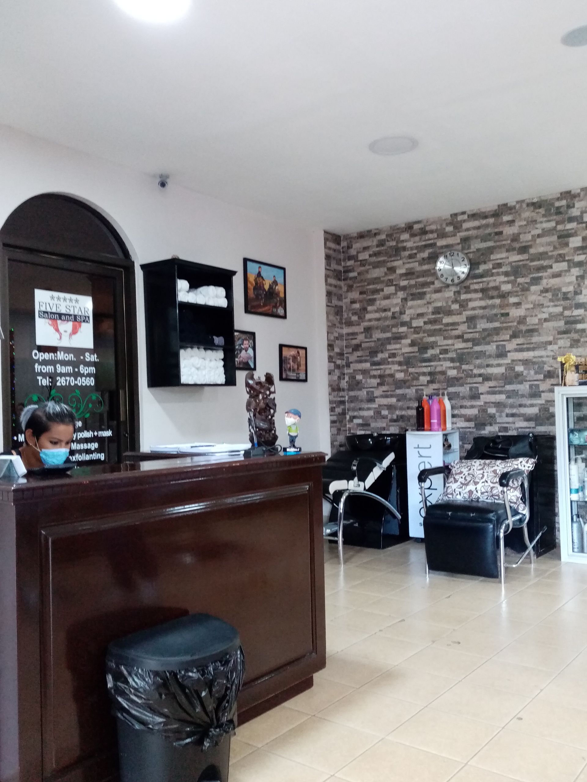 Salon interior with receptionist, waiting area with seating, and textured accent wall.