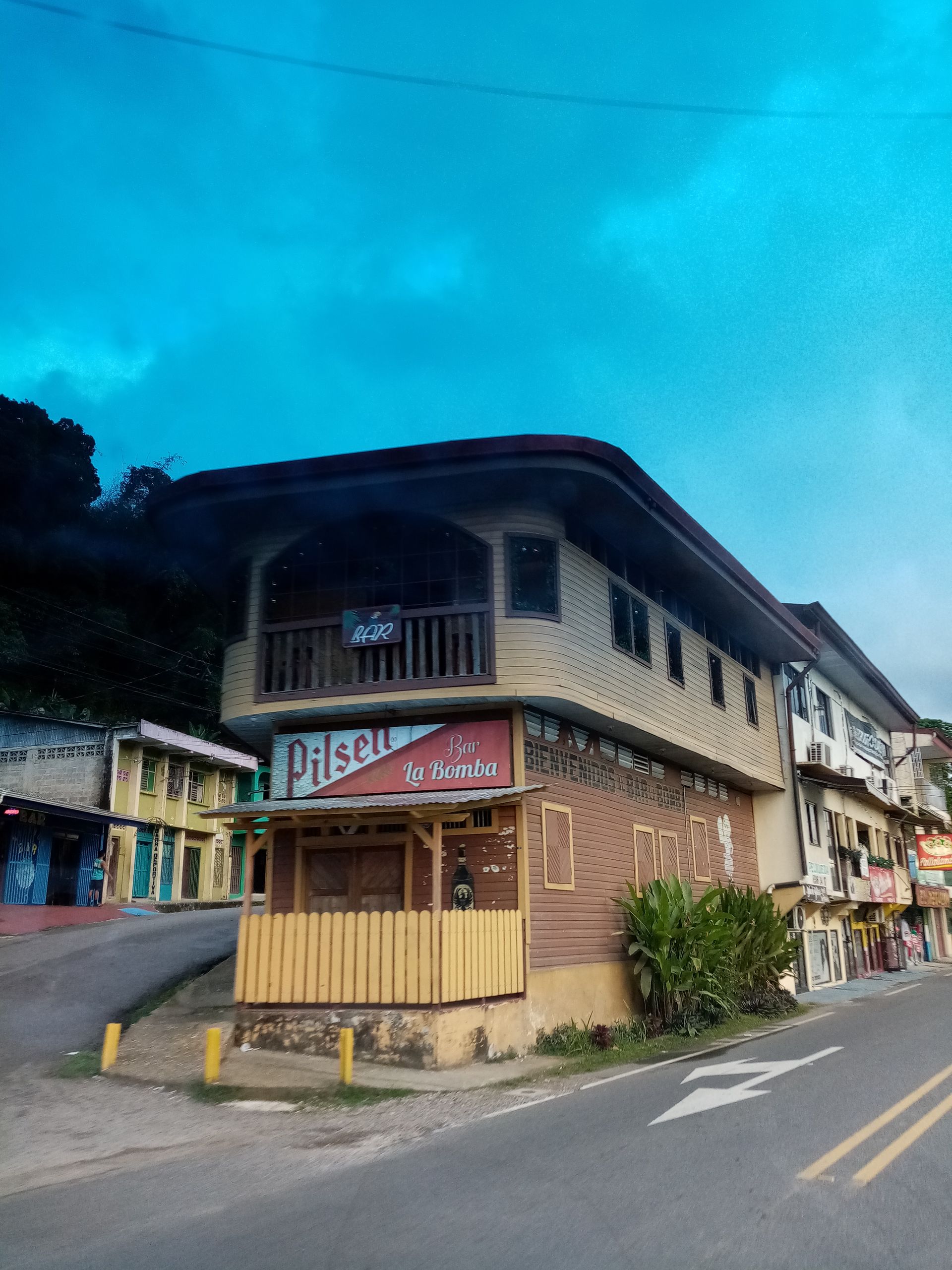 A two-story building with a Pilsner beer sign, a balcony, and a street in front.