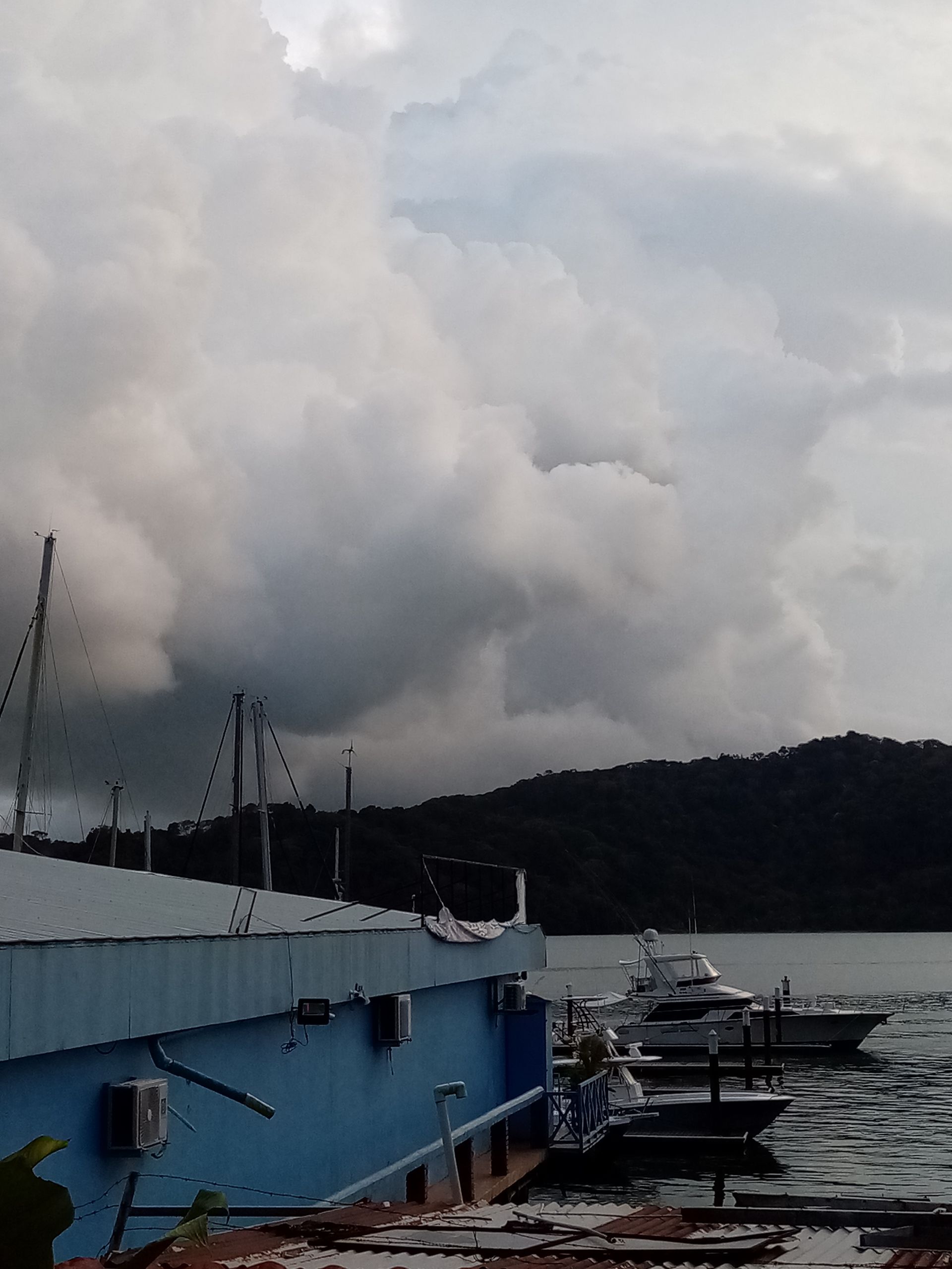 Boats docked near a blue building with dark, cloudy sky overhead.