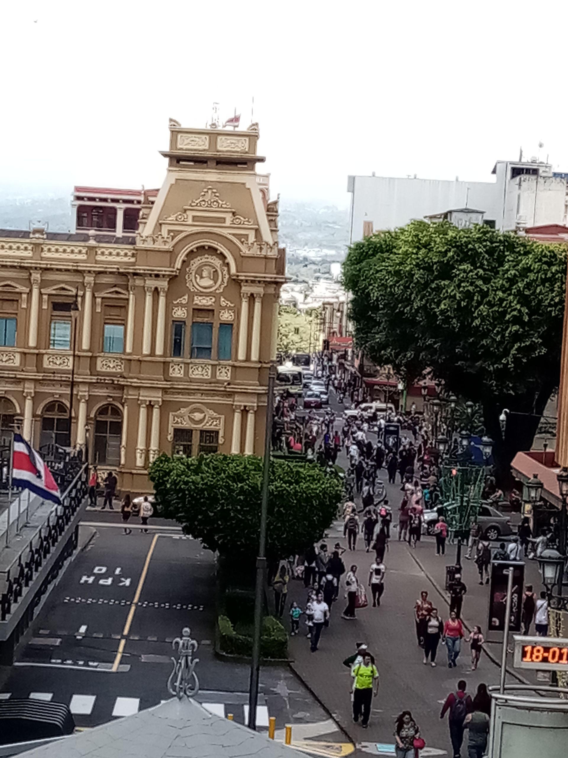 Street scene with people walking, historic building, Costa Rican flag, San José, Costa Rica.