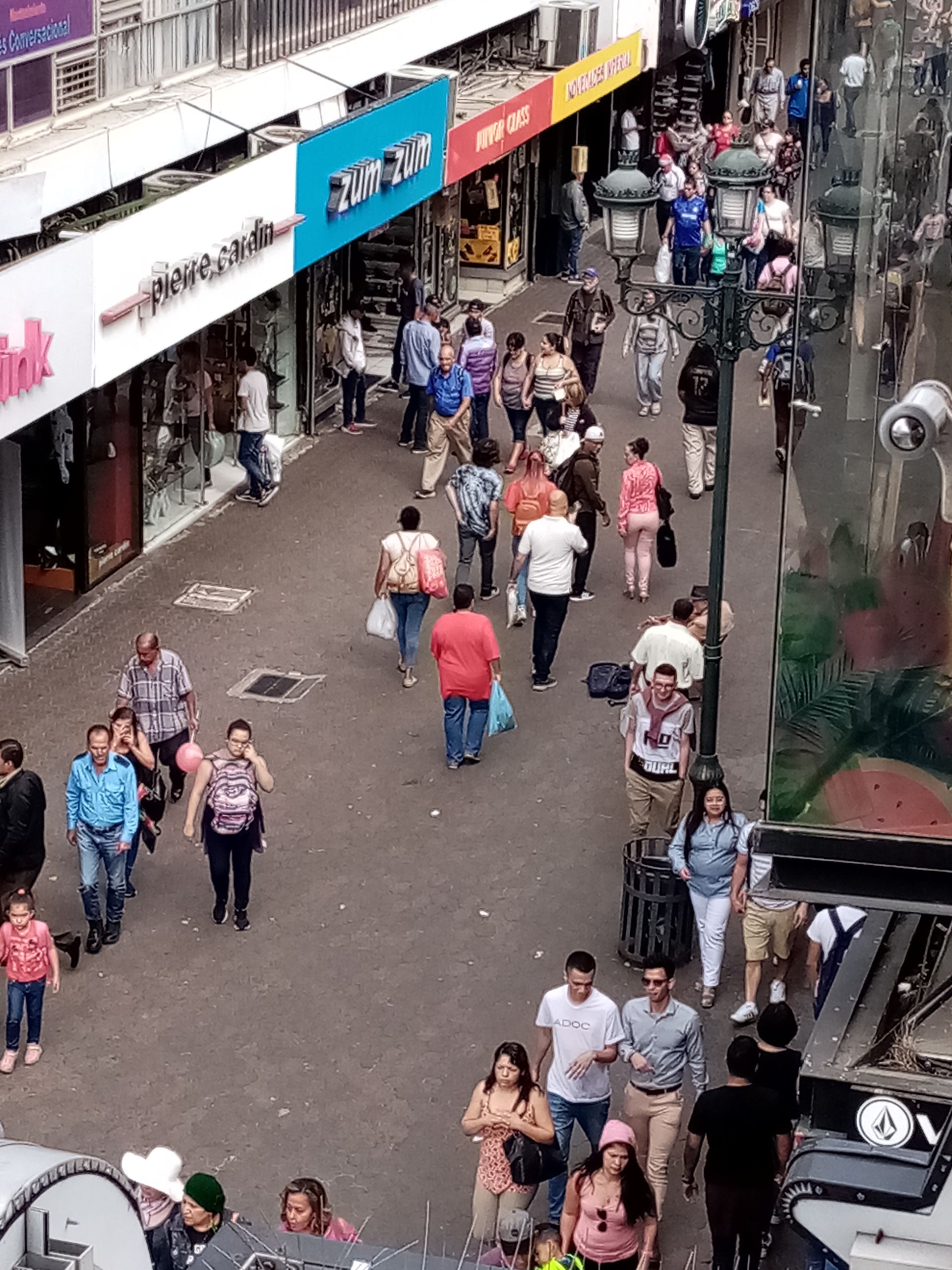 Busy pedestrian street lined with shops, people walking in both directions.