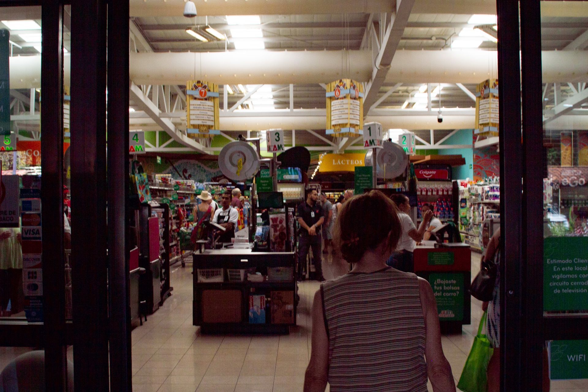 View of store interior from entrance, shoppers, shelves, checkout areas.
