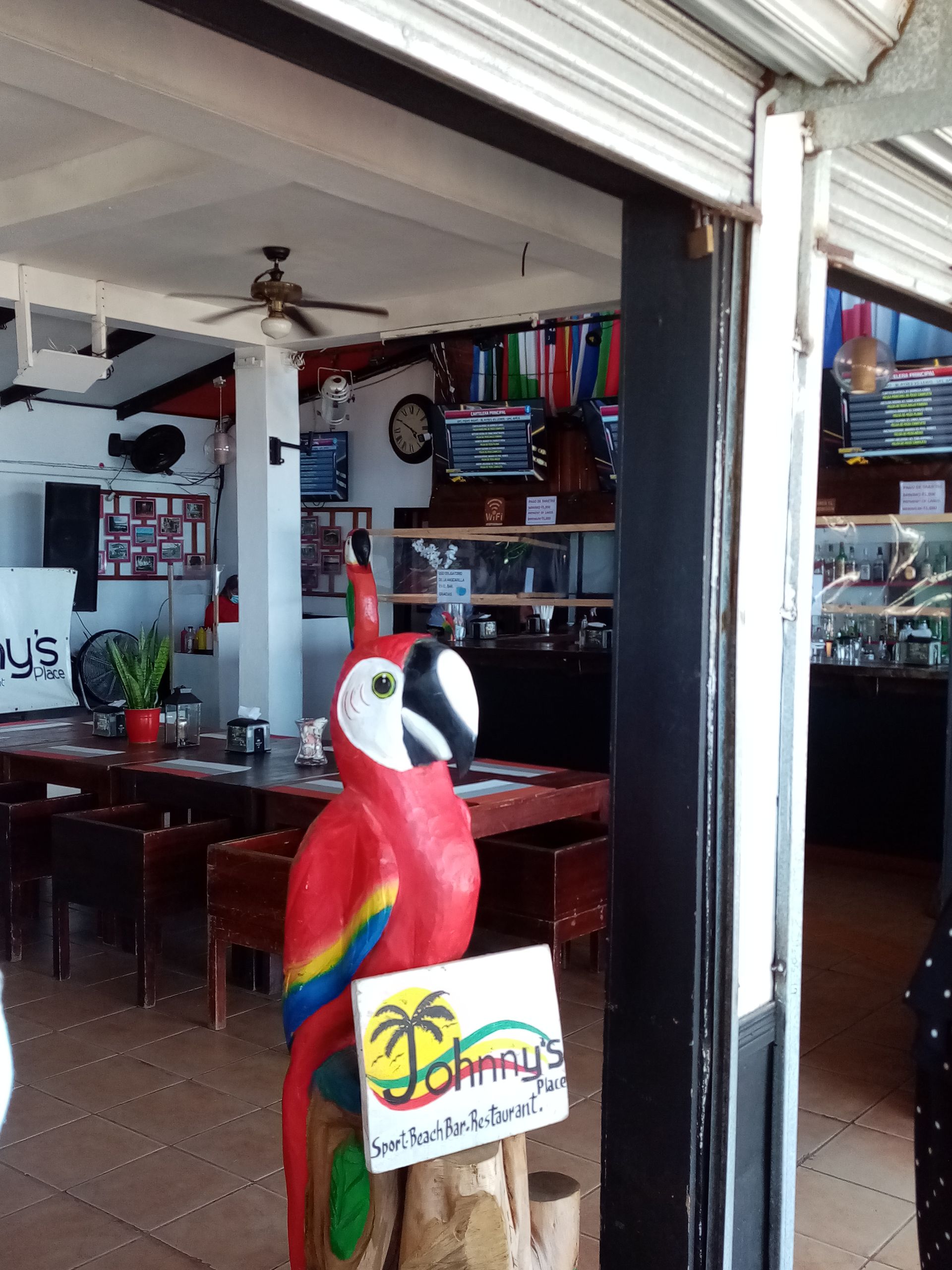Entrance to Johnny's restaurant, featuring a parrot statue, with tables and bar visible inside.