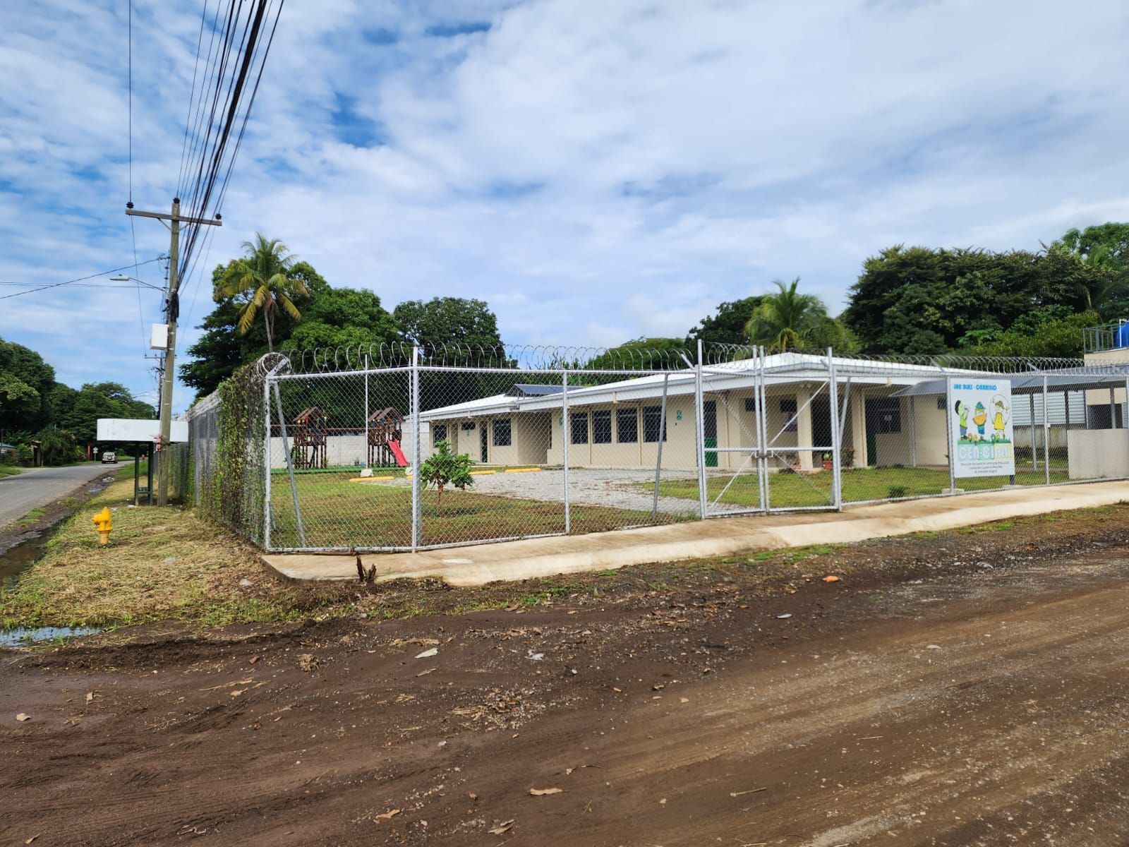 Building with fence, a power pole, and cloudy sky.