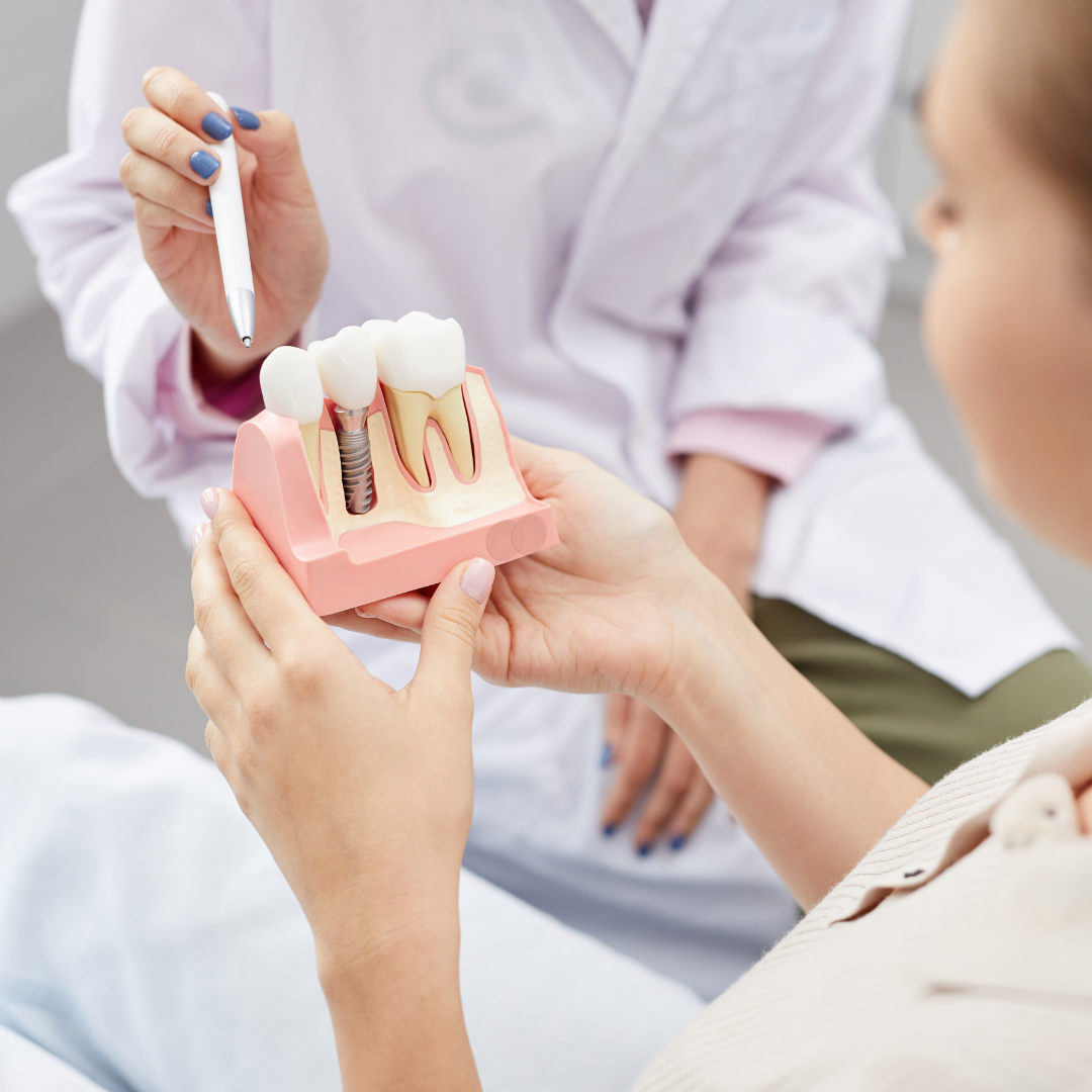 Dentist showing a patient a model of a dental implant with a pen.