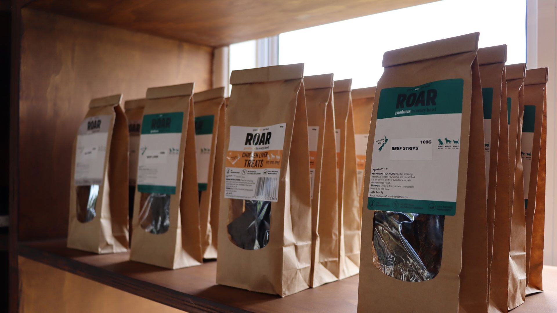 A row of brown bags sitting on top of a wooden shelf.