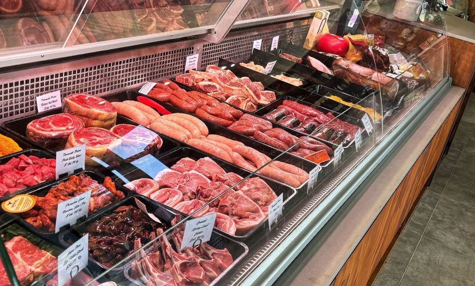 A butcher shop display case filled with lots of meat.