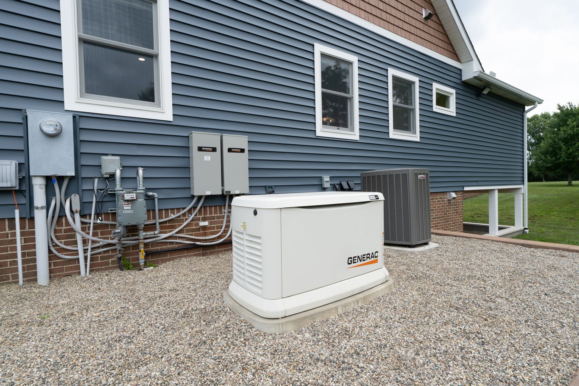 White backup generator beside a blue house on a gravel yard