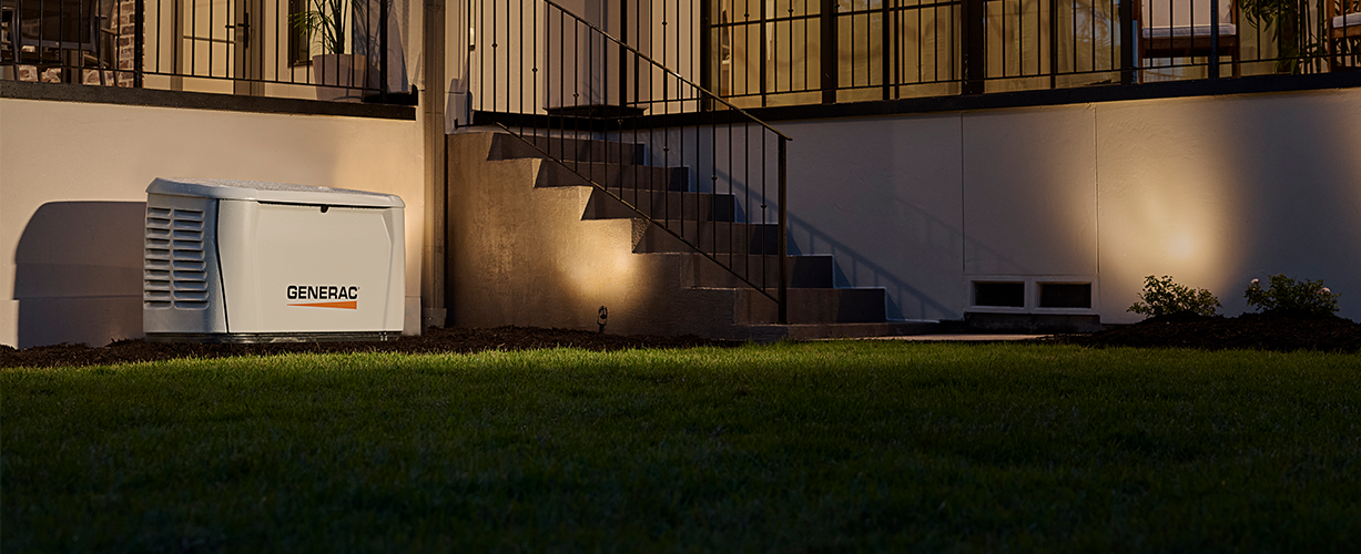 Portable generator beside a house at night, lit by warm exterior lights