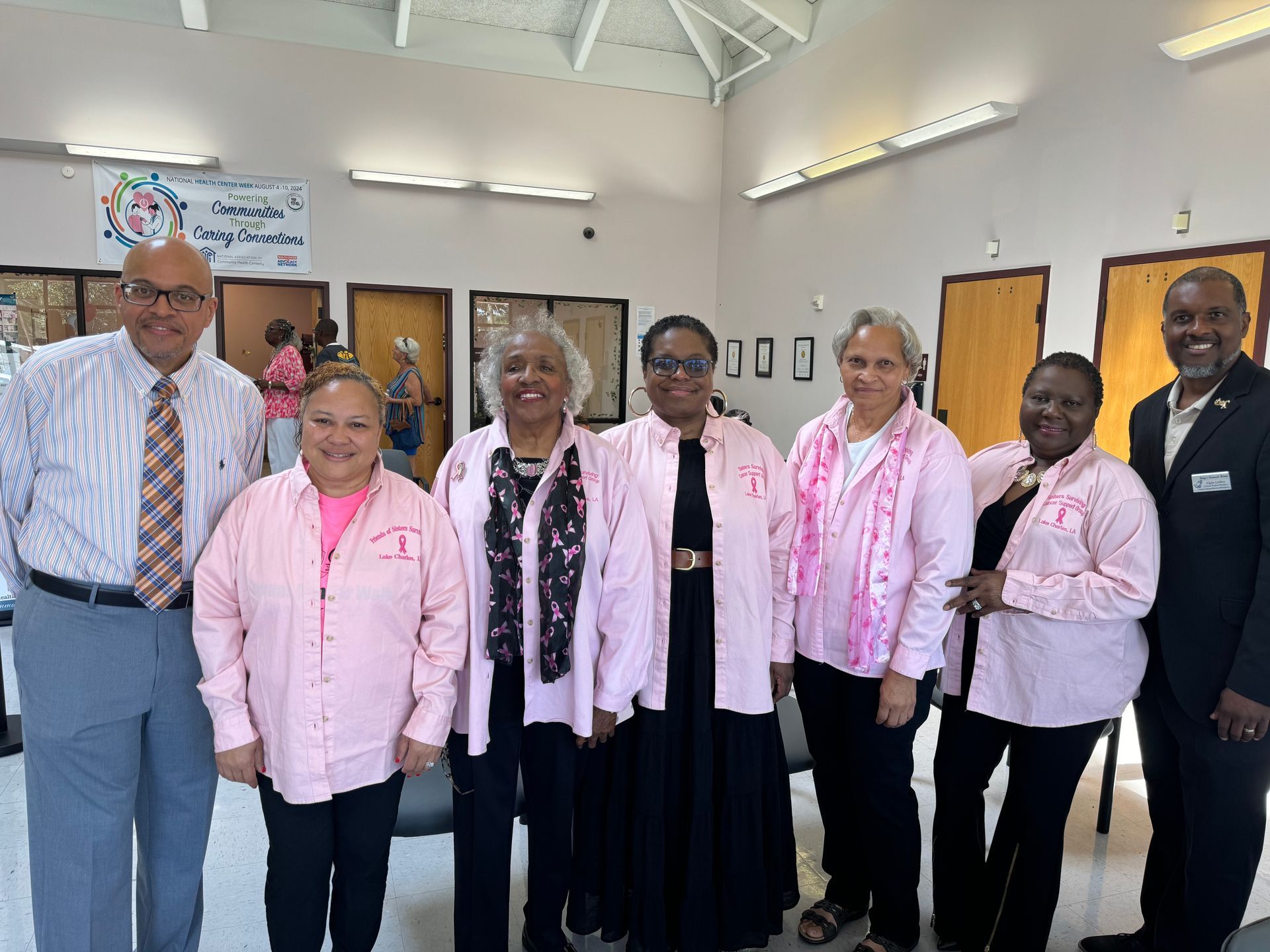 A group of people wearing pink shirts are posing for a picture.