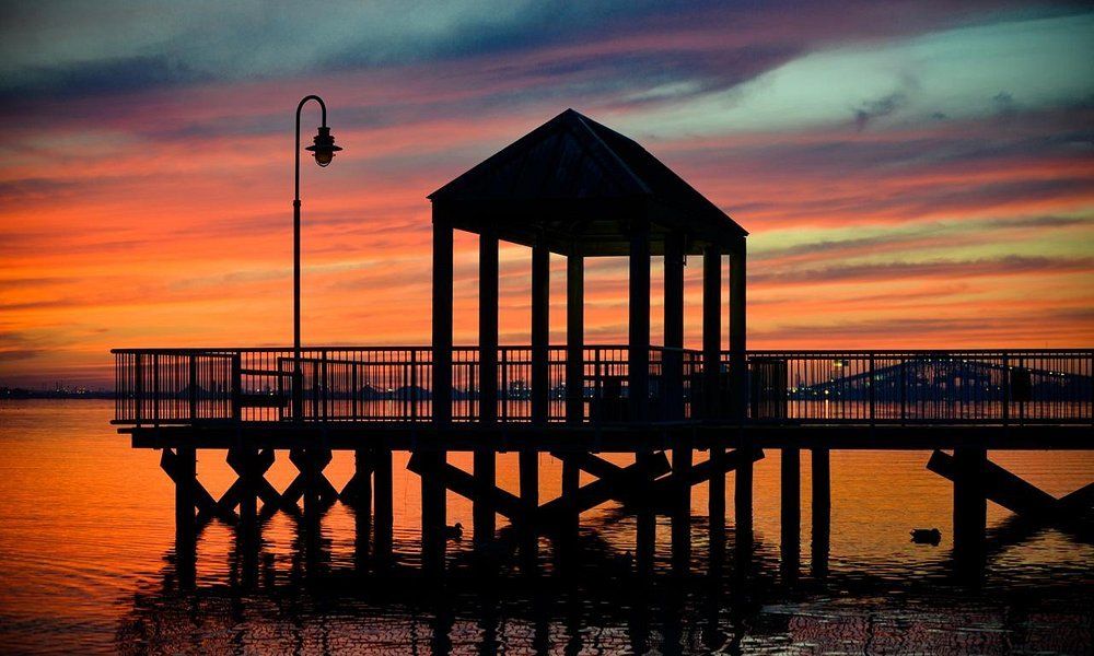A pier with a gazebo on top of it at sunset