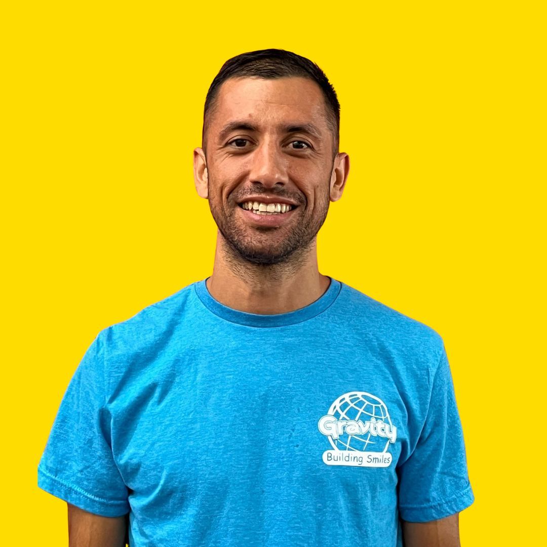 Smiling man in a blue T-shirt against a bright yellow background