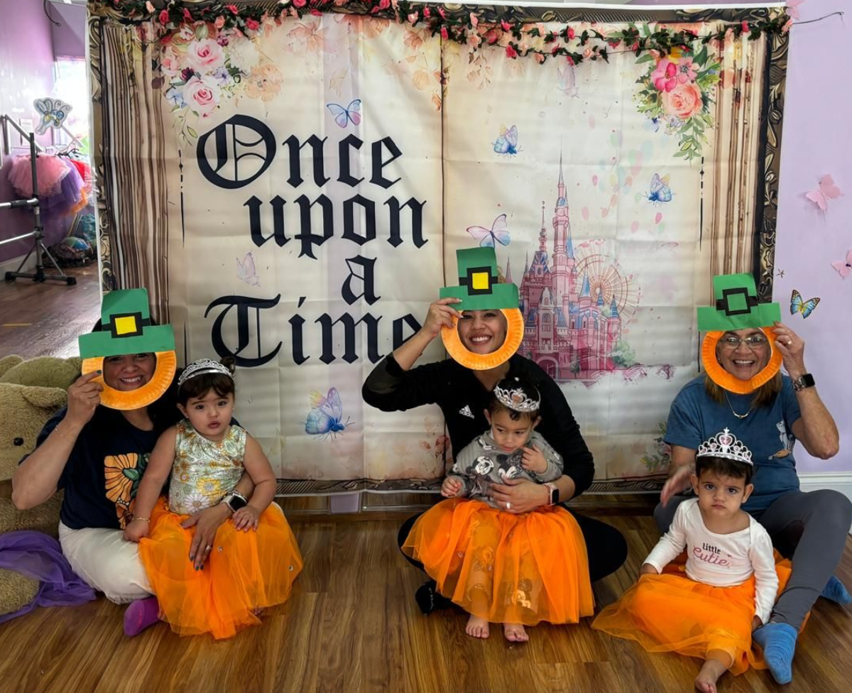 Children in Halloween hats pose in front of an “Once upon a time” backdrop with orange tulle skirts.