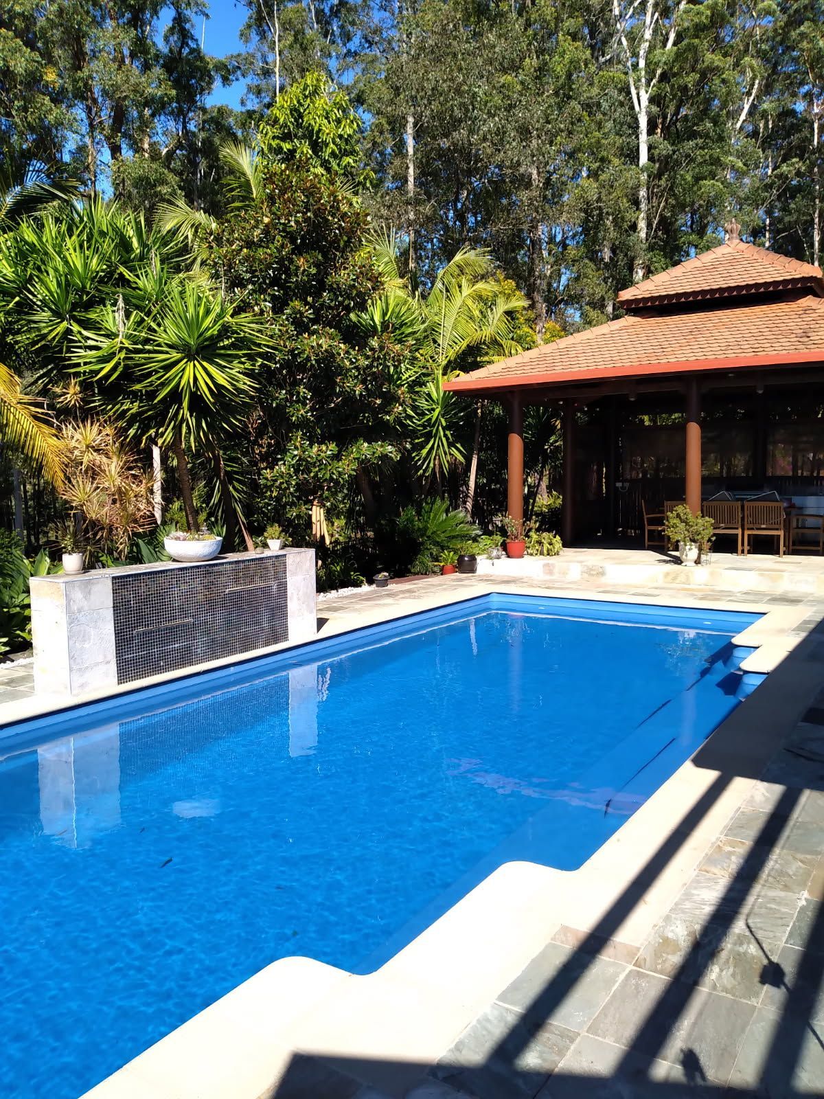 A large swimming pool with a gazebo in the background