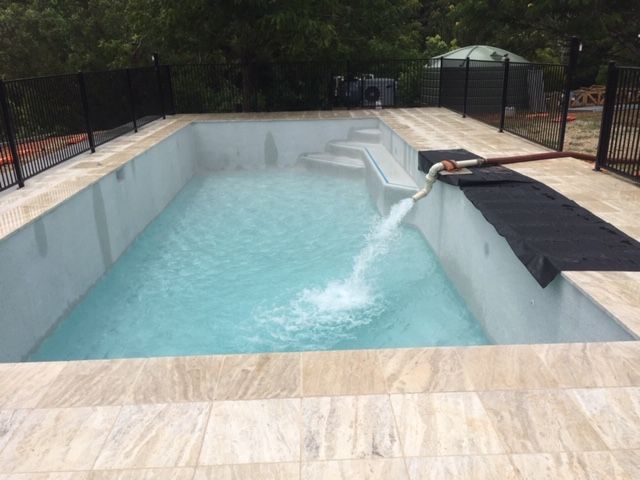 A hose is spraying water into a swimming pool.