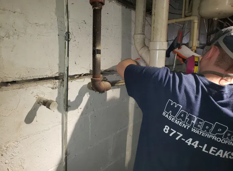 A man is working on a pipe in a basement.