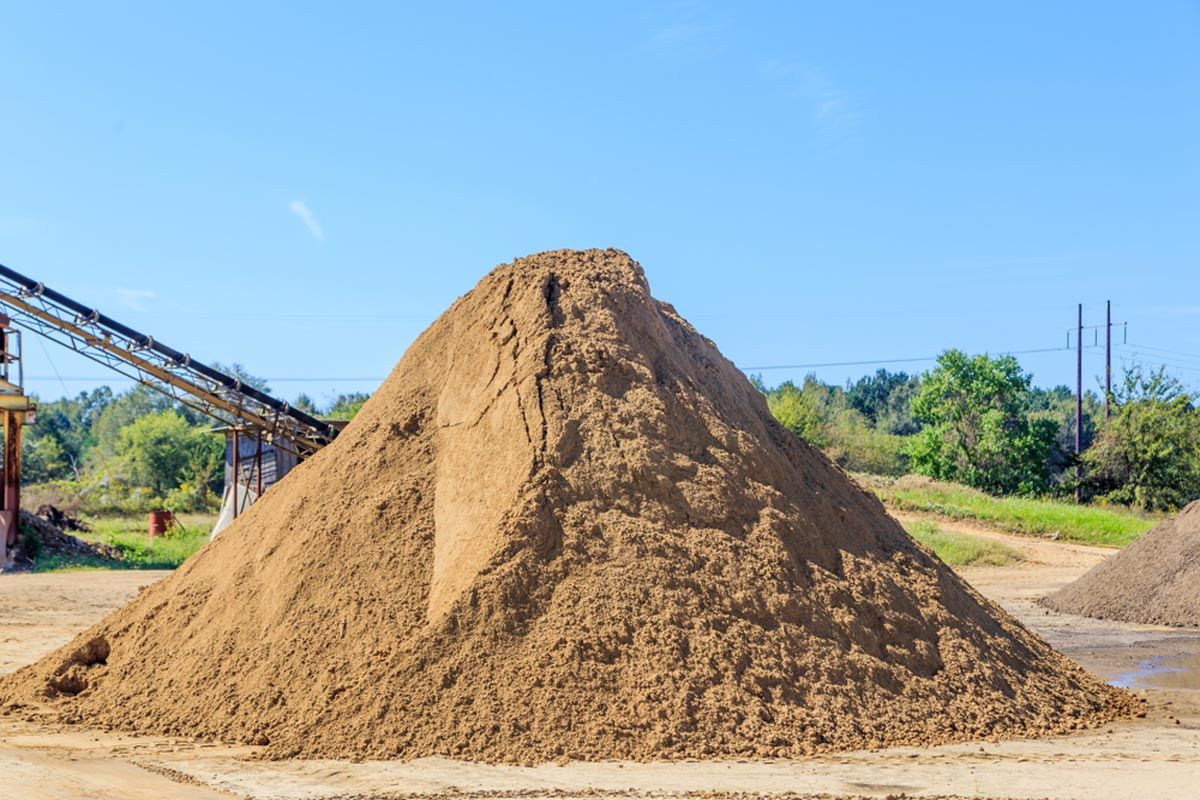 A large pile of dirt is sitting in front of a conveyor belt.