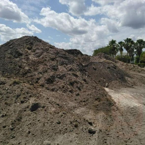 A pile of dirt is sitting on top of a dirt road.