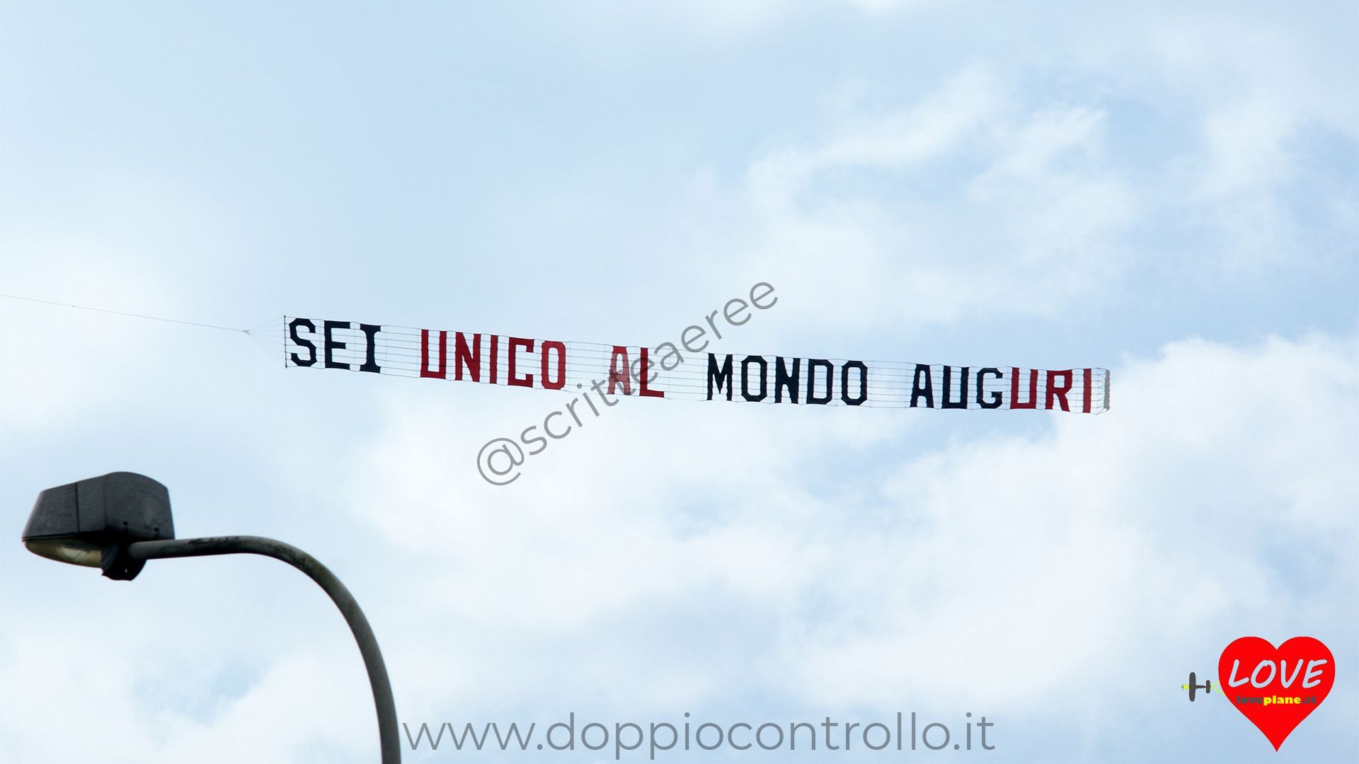 dedica aerea, aereo con striscione auguri, scritta in cielo
