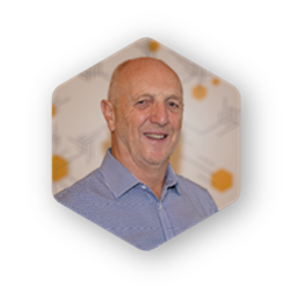 Bald man in blue shirt smiles inside a hexagonal frame against a blurred background.