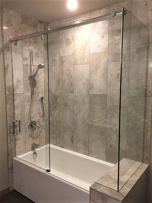 A bathroom with a bathtub and a shower stall with sliding glass doors.