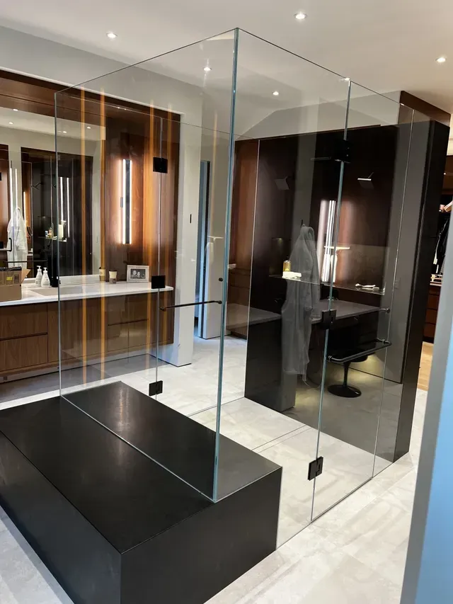 Modern bathroom with a glass shower enclosure, black tub, and vanity with mirror.