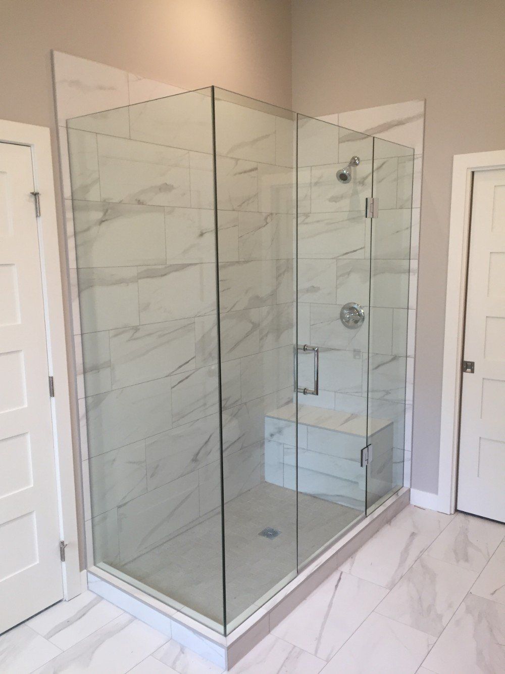 A bathroom with a walk in shower with a glass door