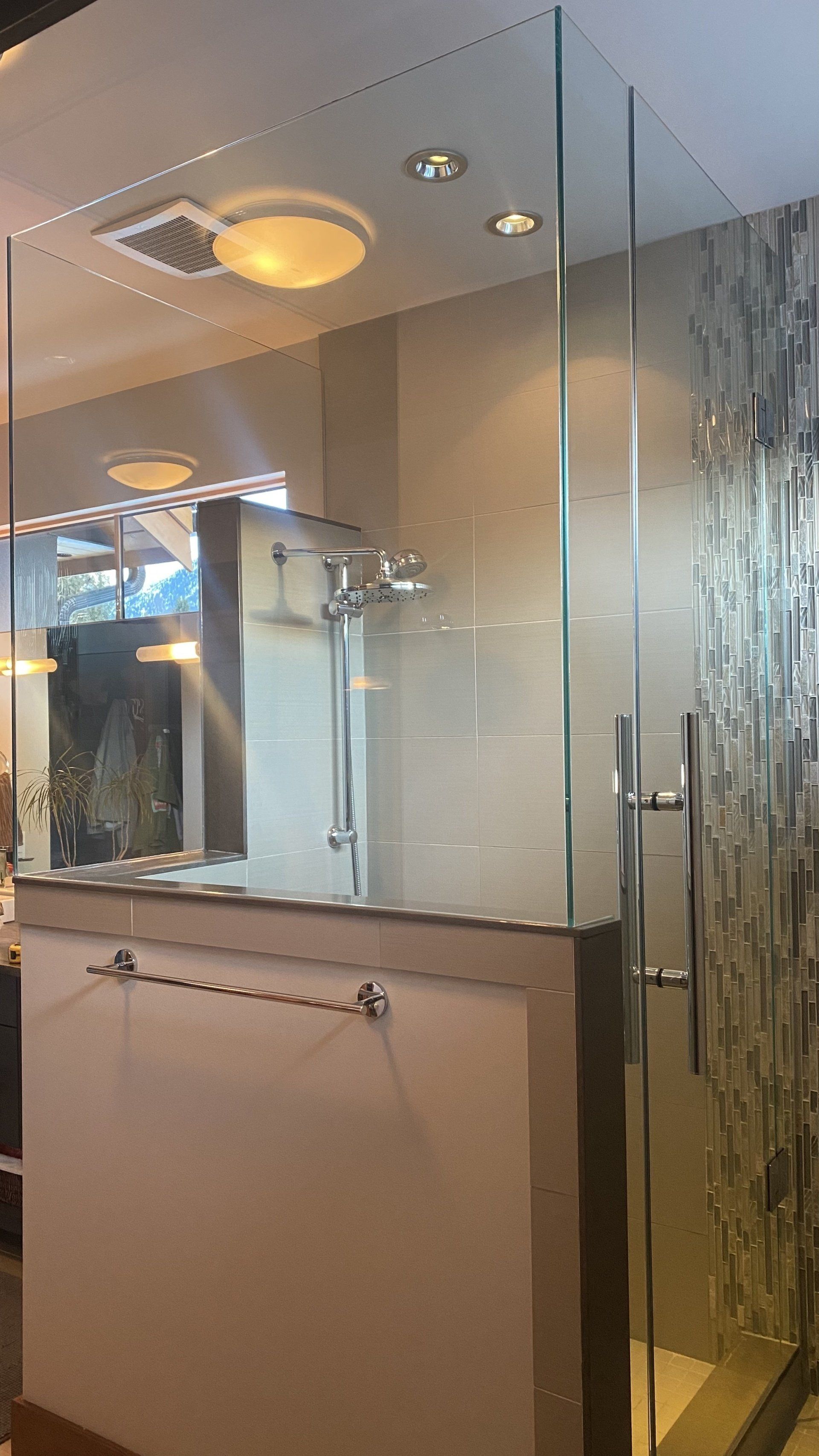 A bathroom with a glass shower door and a mirror.