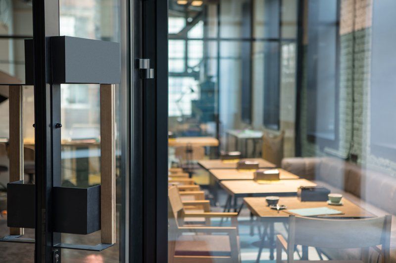 Modern office meeting room seen through a glass door, with wooden tables and chairs inside