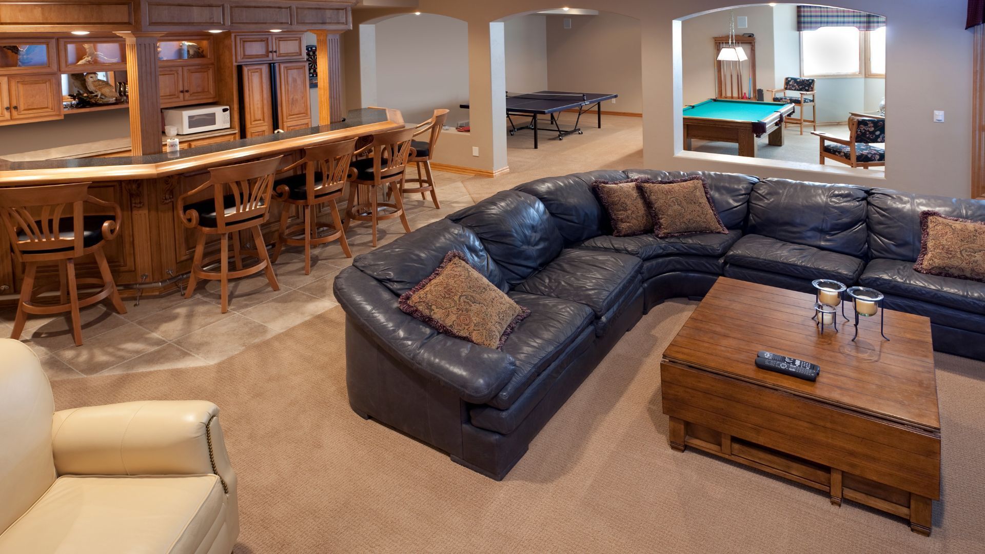 A living room with a large sectional couch and a pool table