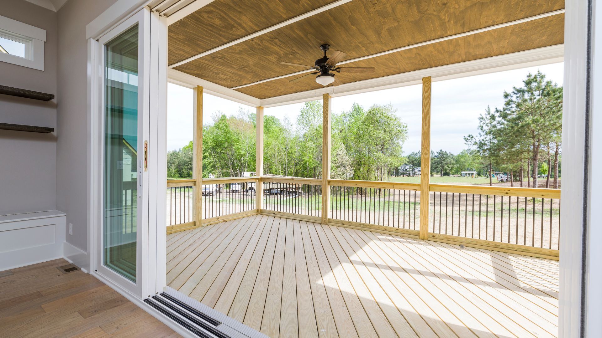 A screened in porch with a ceiling fan and sliding glass doors.