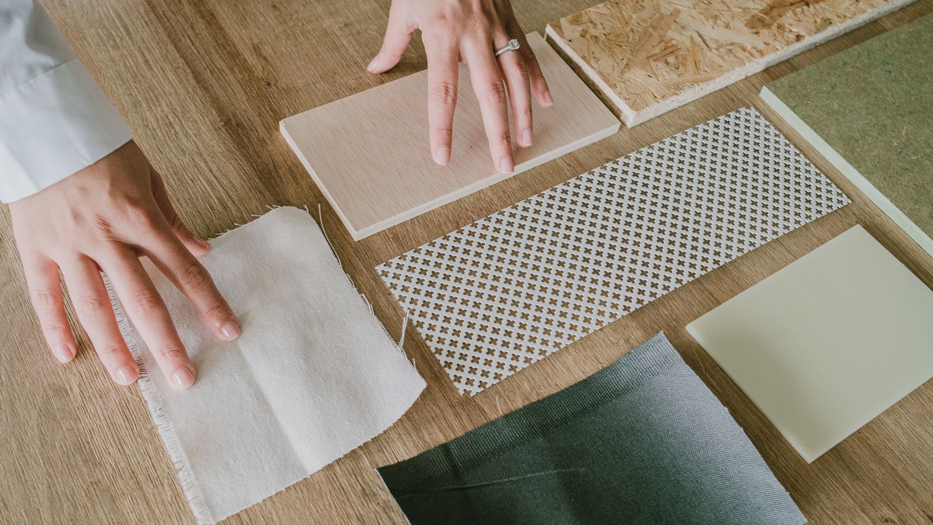 A person is holding a piece of fabric on a wooden table.