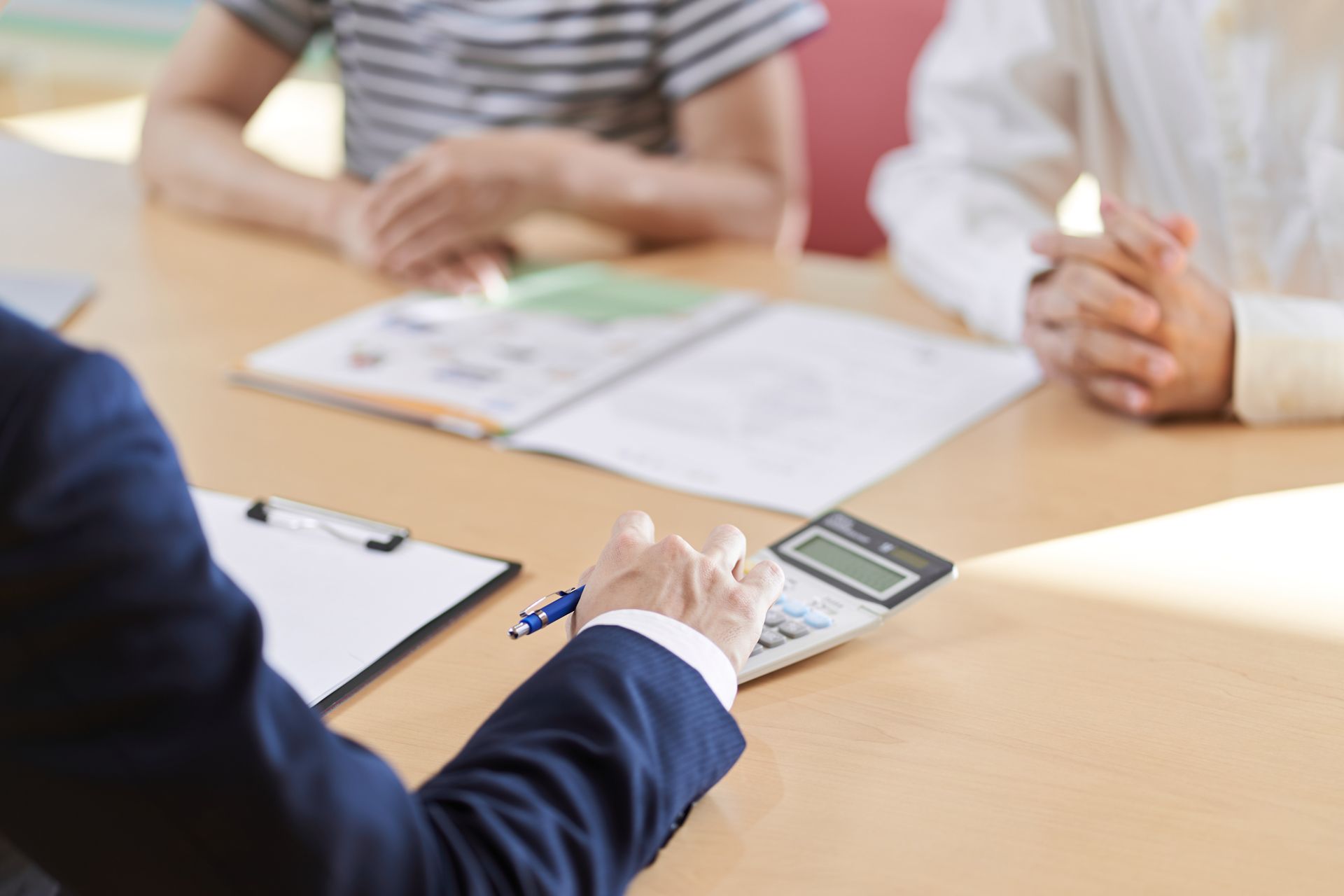 A Group of People Are Sitting at a Table With Papers and a Calculator
