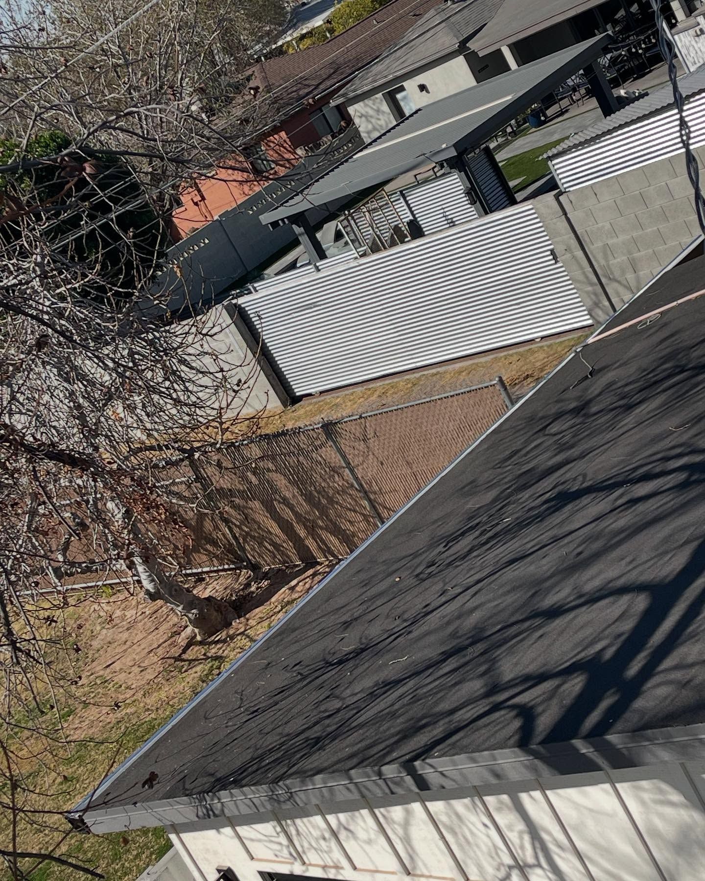 Tilted view of a suburban backyard with gray rooftops, leafless trees, and a chain-link fence