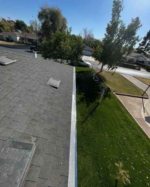 Roof edge overlooking a green lawn and trees on a sunny suburban street