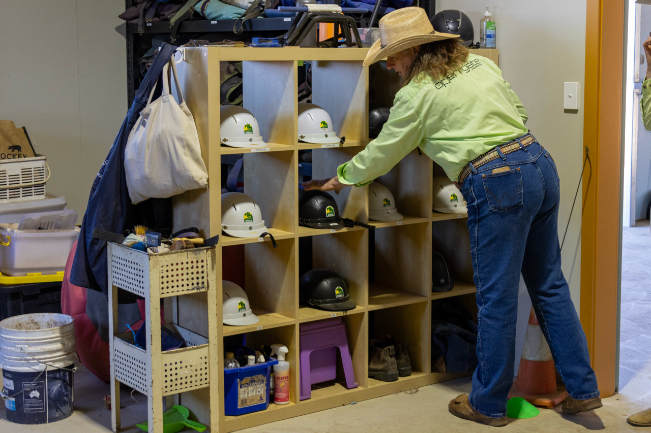 instructor choosing a helmet for a student in the tack room