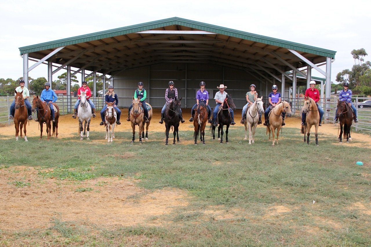 large group of students on horses in front of the covered arena