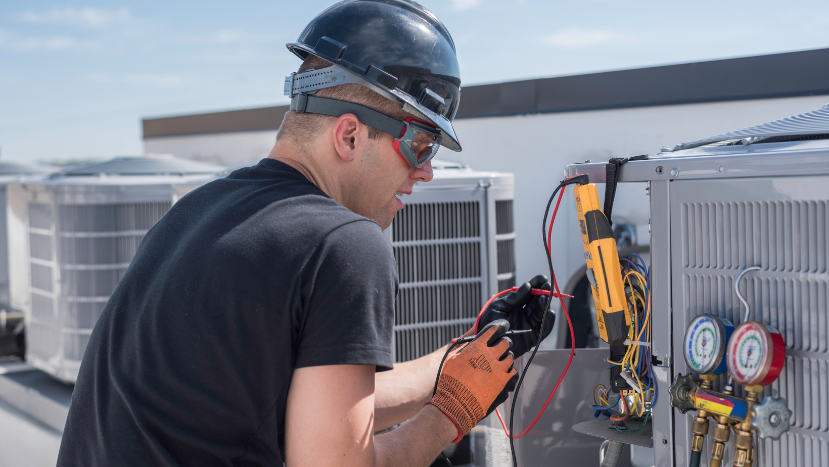 Technician inspecting HVAC unit with gauges and tools on a rooftop