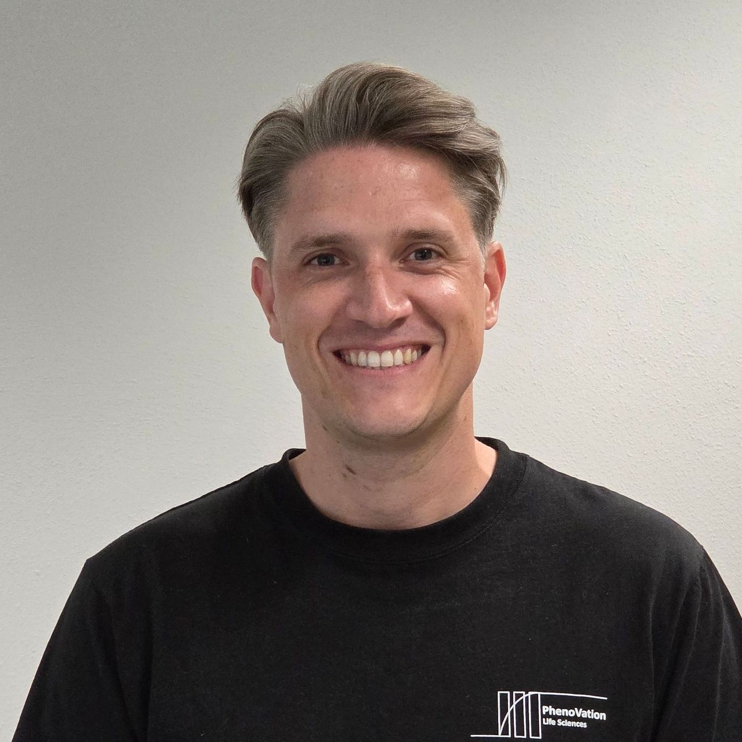 A man is smiling for the camera and wearing a black shirt.