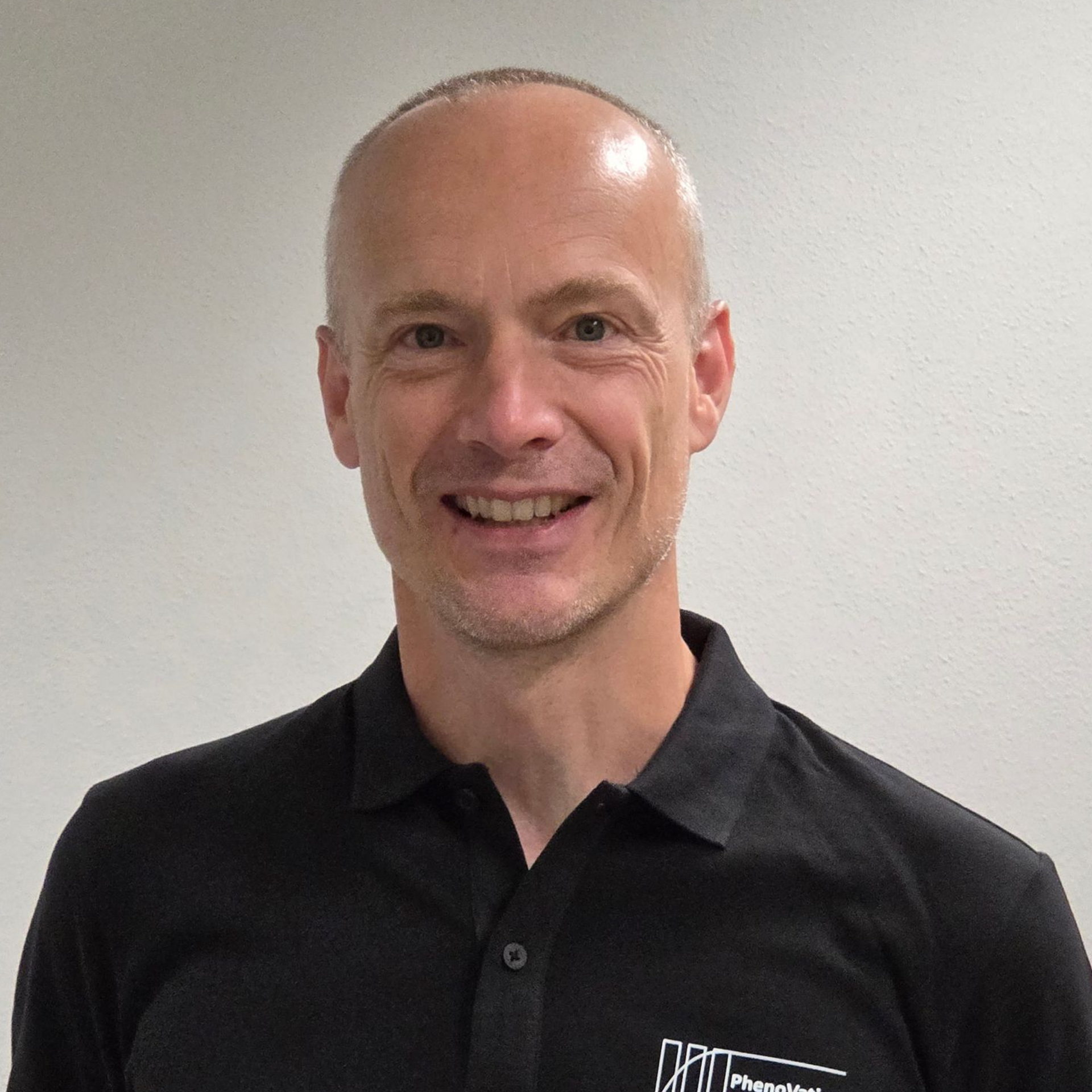 A man is smiling for the camera and wearing a black shirt.