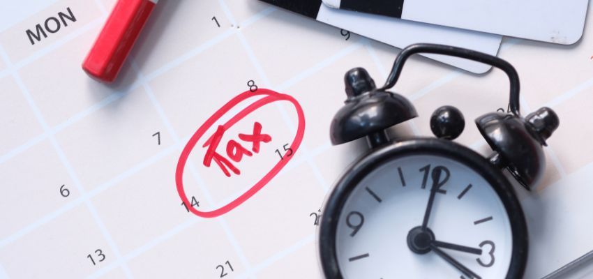 A calendar and an alarm clock that reminds you of the date for small business tax filing.