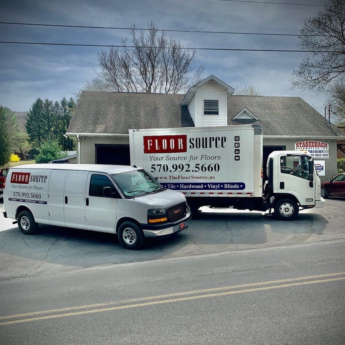 Two white vans are parked next to a flour source truck