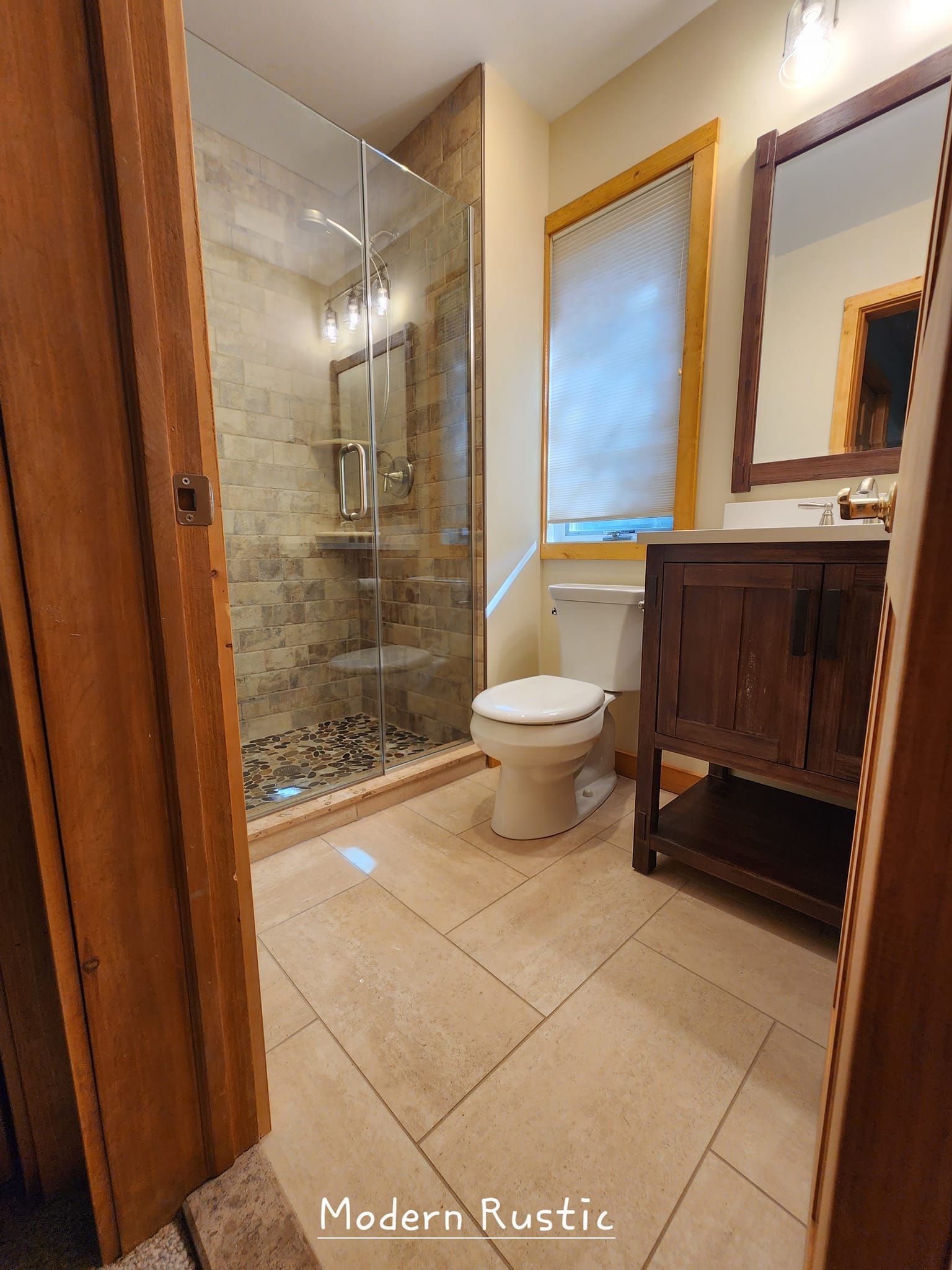A bathroom with a toilet , sink , mirror and walk in shower.